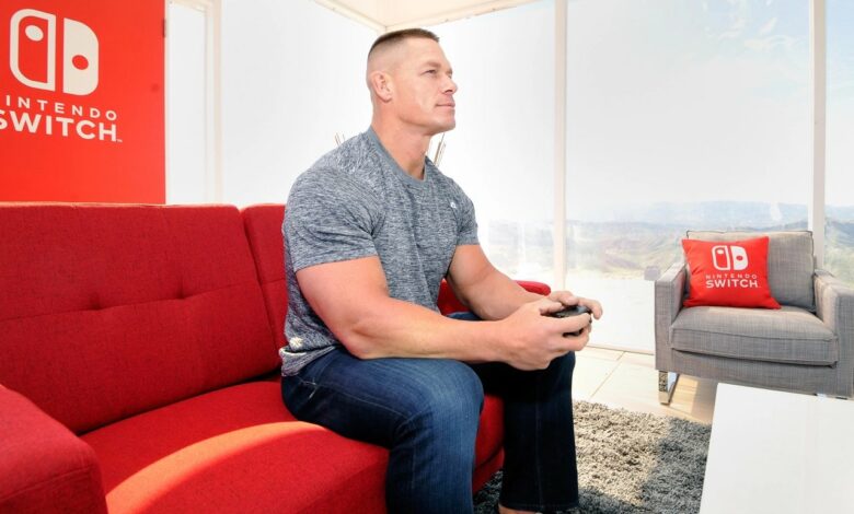 John Cena sitting on a couch playing a Nintendo Switch